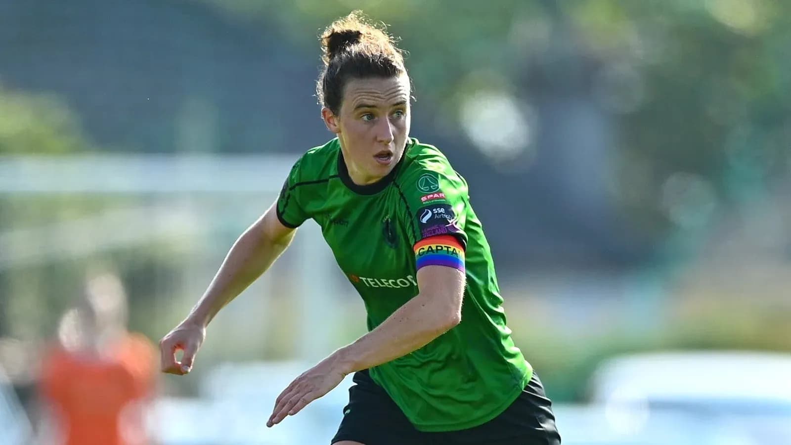 Player in green kit with captain's armband running