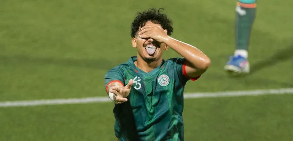 Player celebrating goal with playful gesture on field