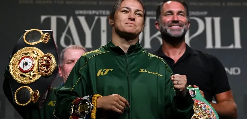 Katie Taylor holding championship belts at press event