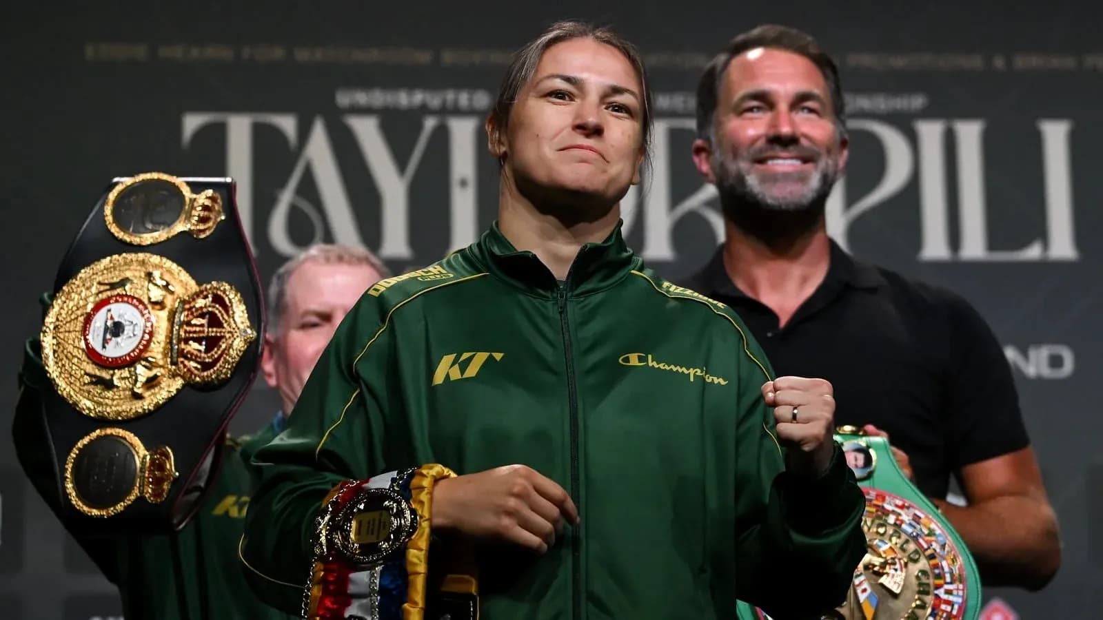 Katie Taylor holding championship belts at press event