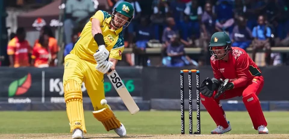 Batsman hitting the ball while wicketkeeper crouches