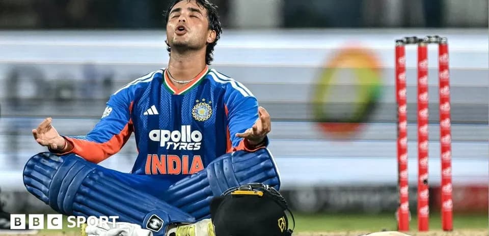 Cricketer sitting on field with arms raised