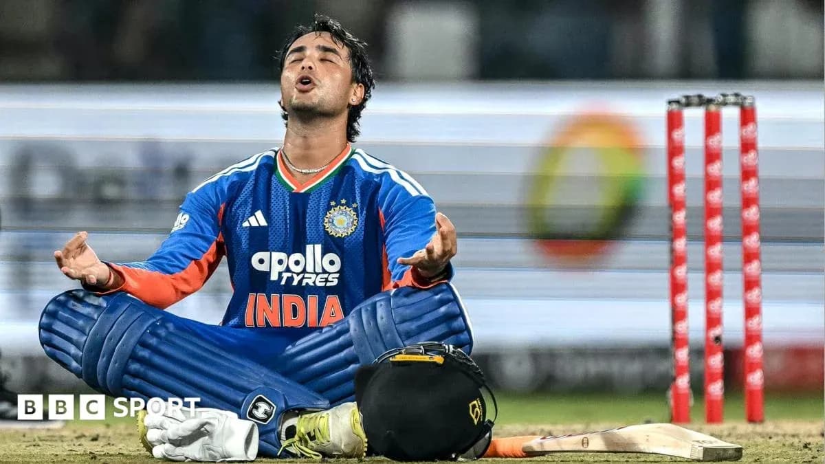 Cricketer sitting on field with arms raised