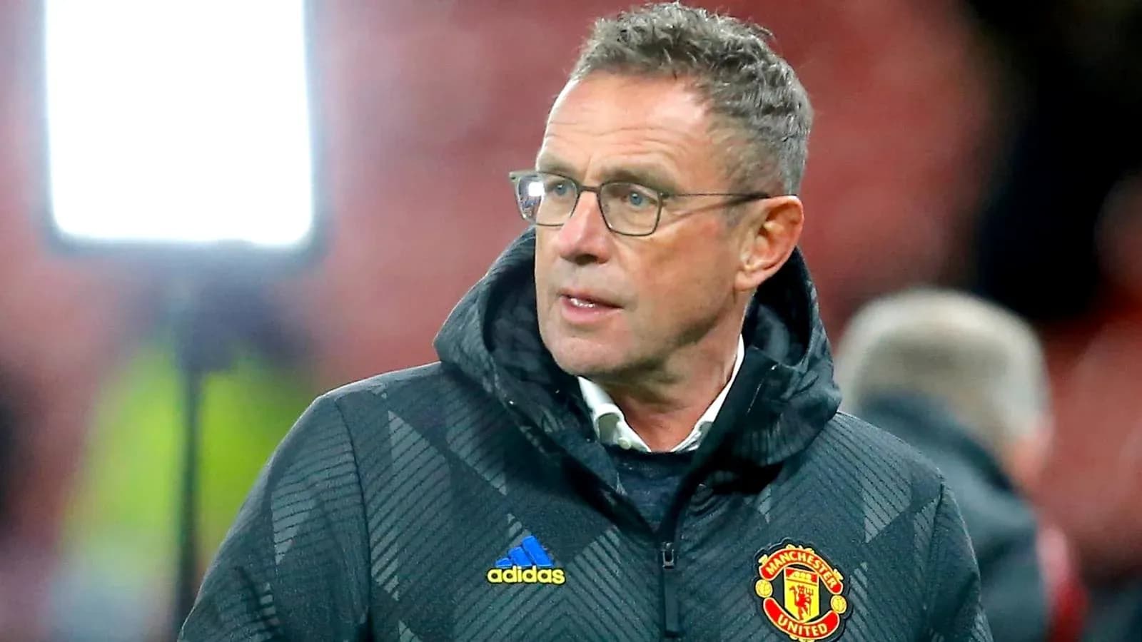 Coach wearing Manchester United jacket during match