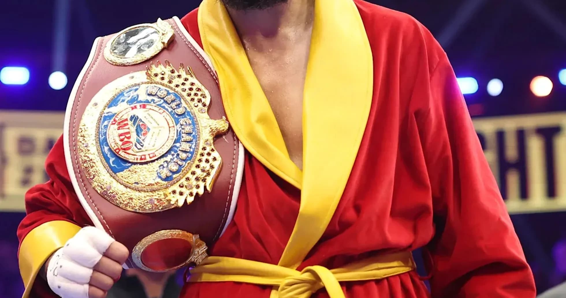 Boxer wearing red robe holding championship belt