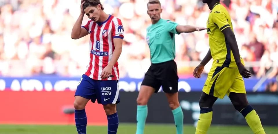 Player holding head with referee signaling during match