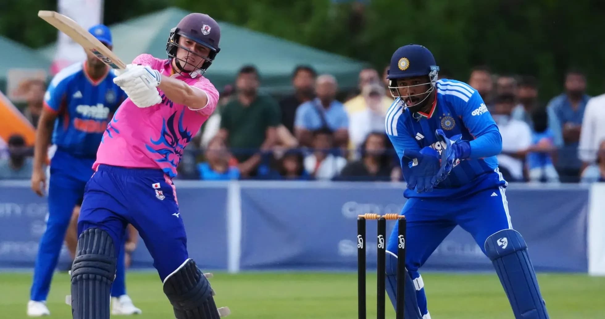 Batsman hitting ball while wicketkeeper prepares to catch