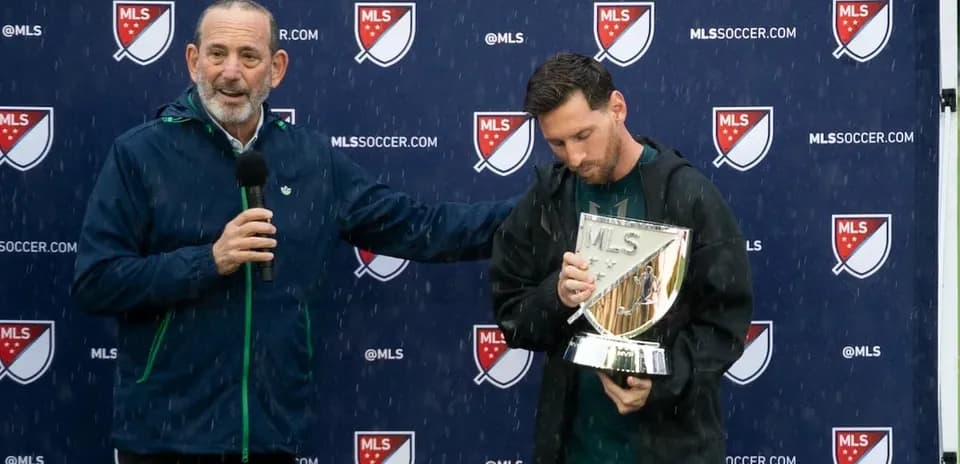 MLS commissioner presenting trophy to player in rain