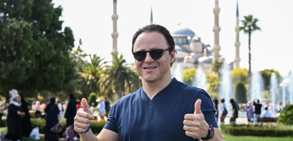 Person giving thumbs up in park with mosque