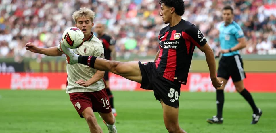 Player kicking ball while opponent attempts to intercept
