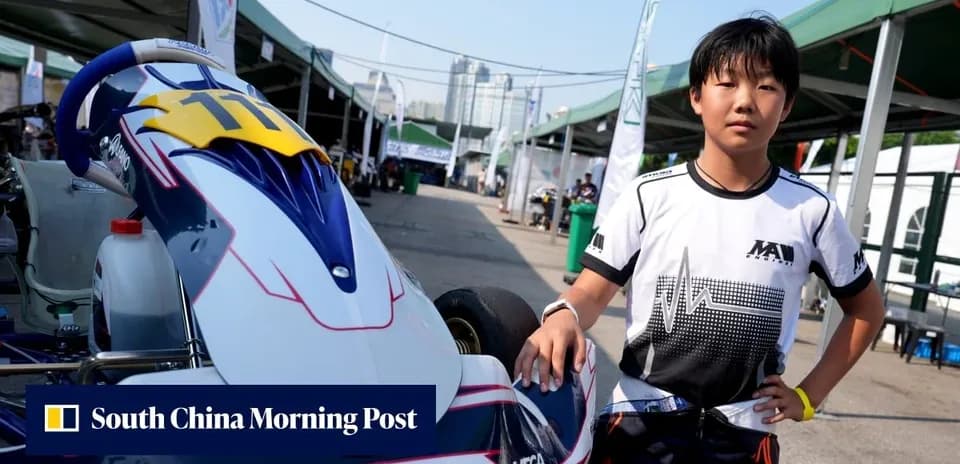 Young racer posing beside kart in paddock