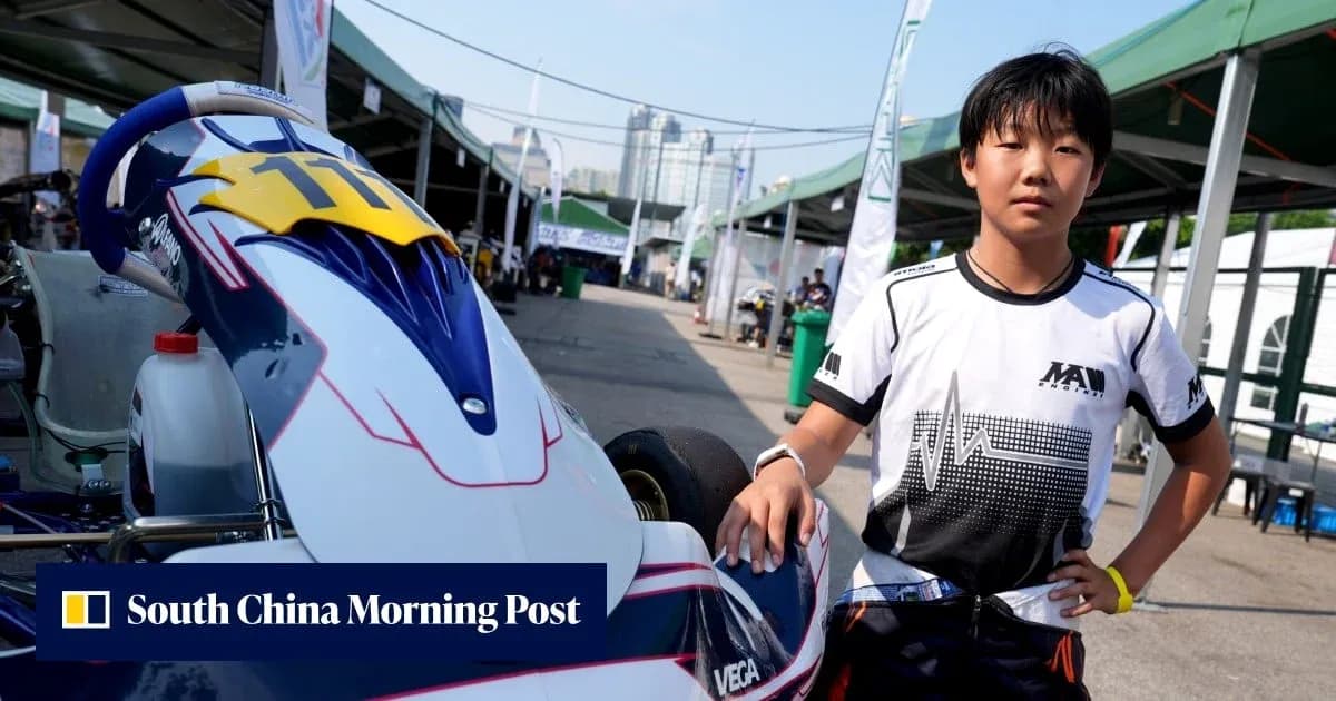 Young racer posing beside kart in paddock