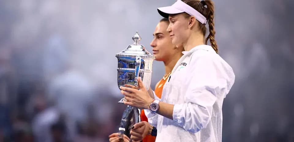 Two tennis players holding trophies during ceremony