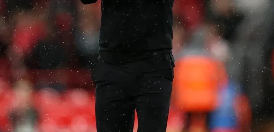 Manager applauding fans during rainy match