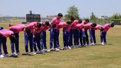 Cricket team bowing in unison on the field