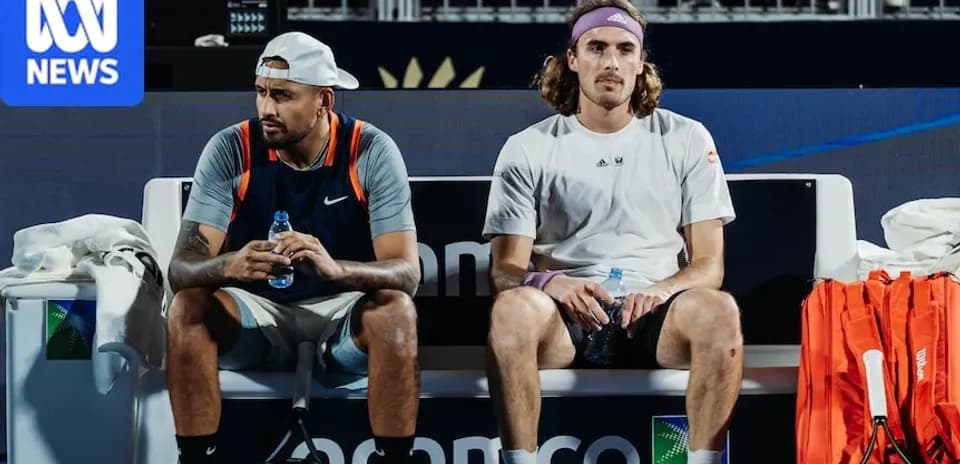 Two tennis players seated on bench during match