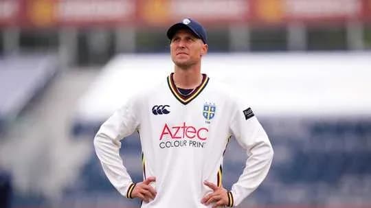 Cricketer in white uniform looking up at the sky