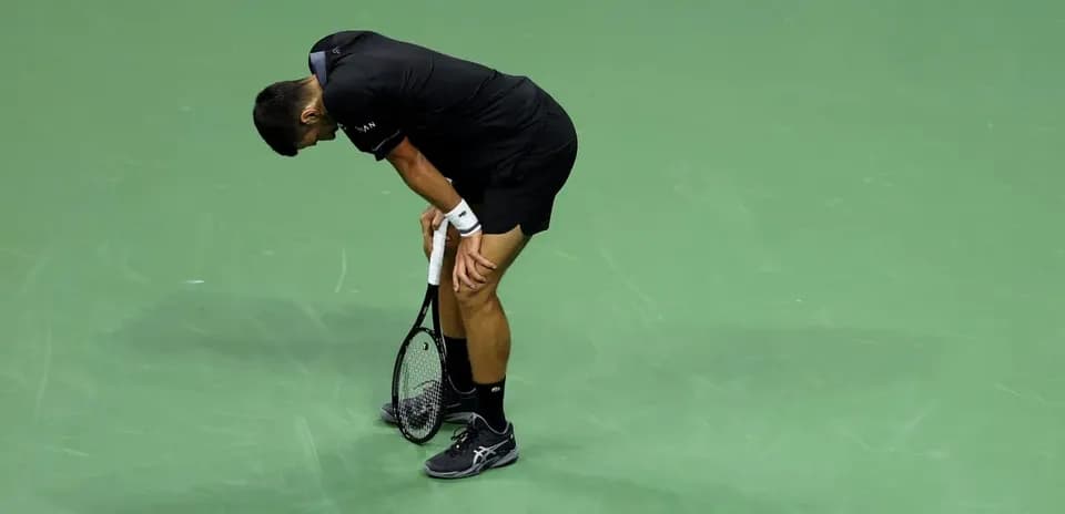 Player bent over holding tennis racket on court