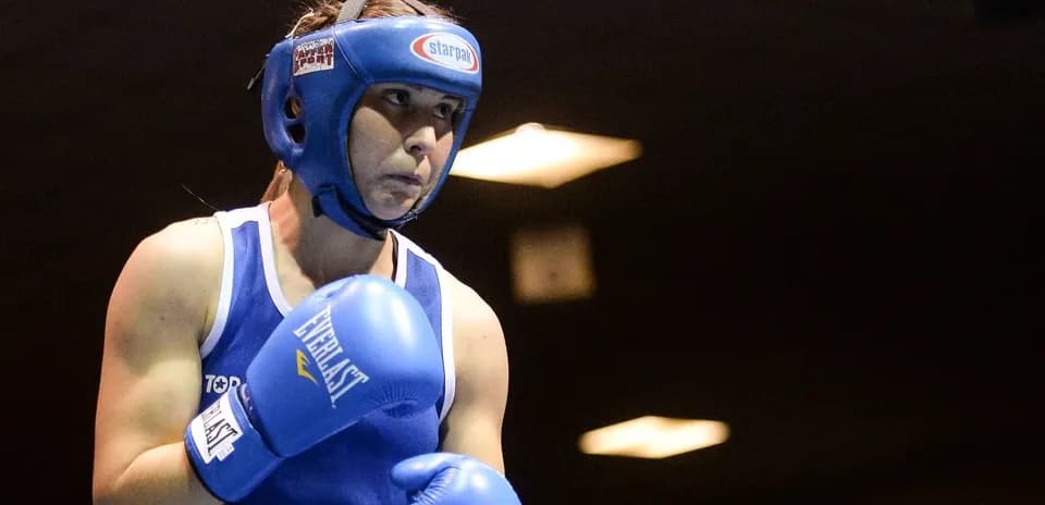 Female boxer in blue gloves preparing to fight