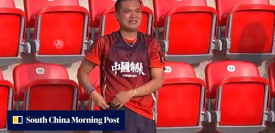 Fan in orange jersey stands in empty stadium seats