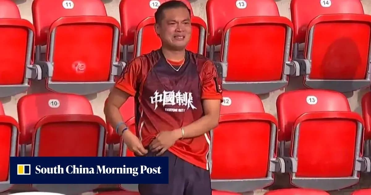 Fan in orange jersey stands in empty stadium seats
