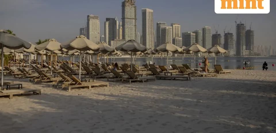 Beach loungers with umbrellas and city skyline