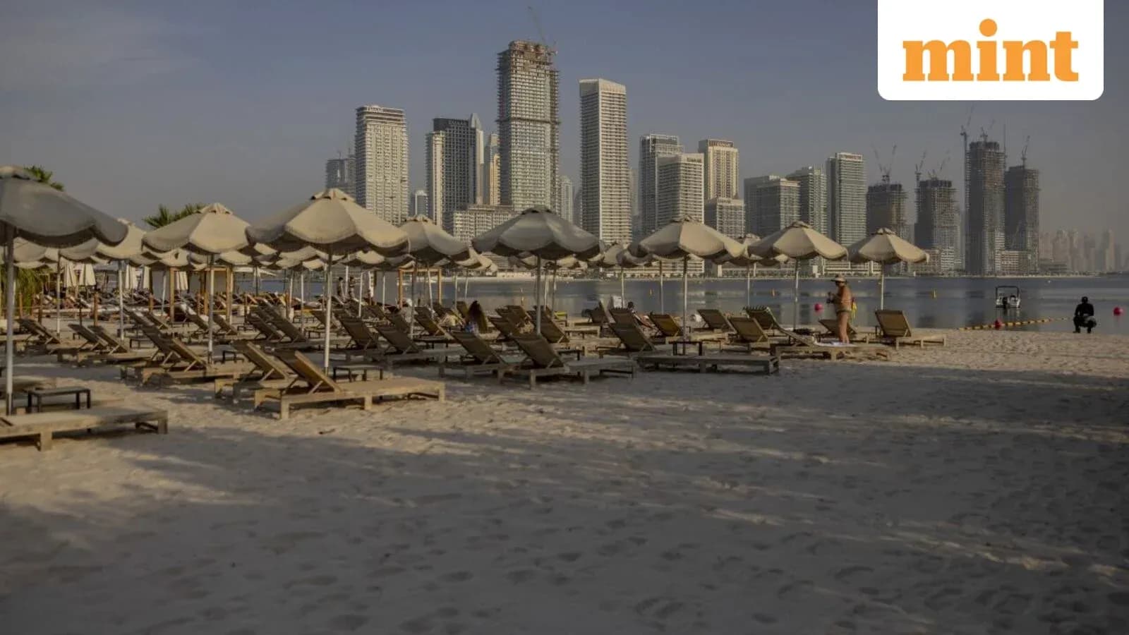Beach loungers with umbrellas and city skyline