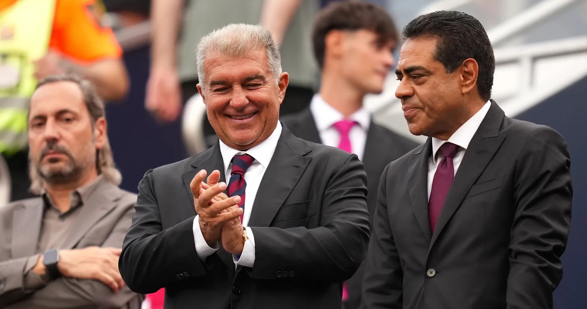 Three men in suits at a sporting event
