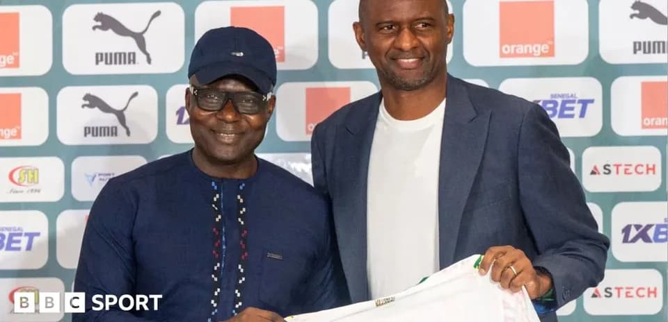 Two men holding a football shirt at a press event