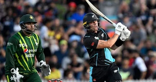 Batsman hitting ball with bowler in background