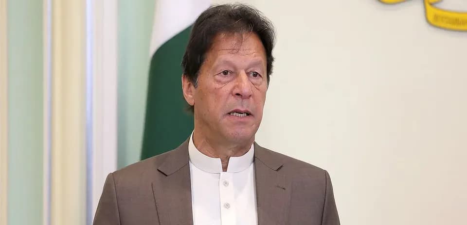 Man speaking at podium with Pakistani flag backdrop