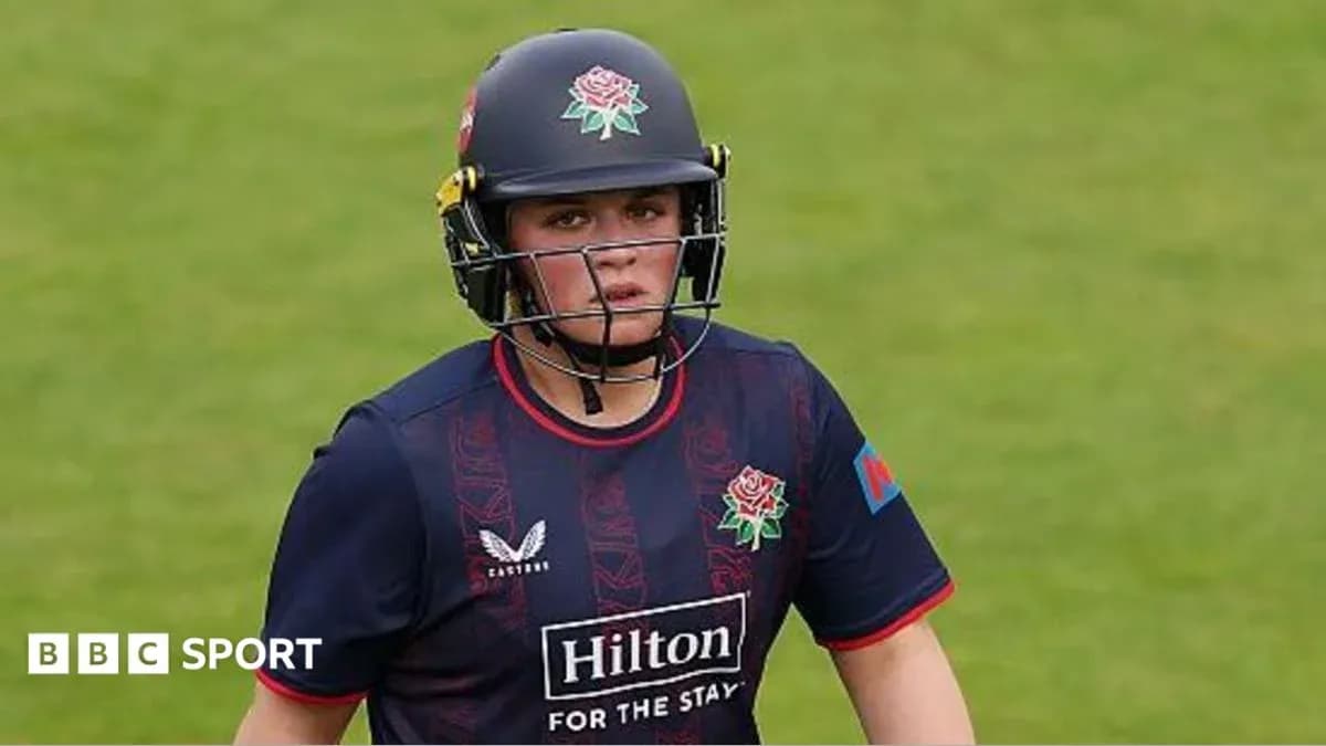 Cricketer wearing helmet and team uniform on field