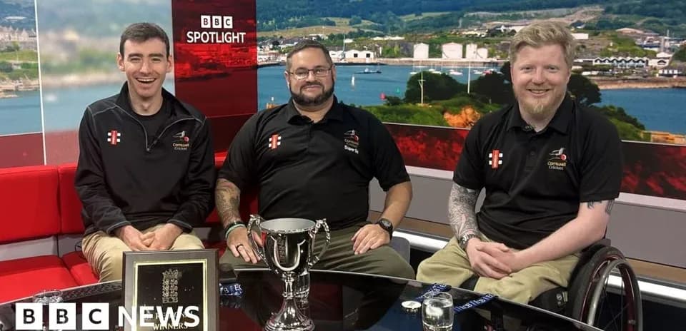 Three men seated with a trophy on set
