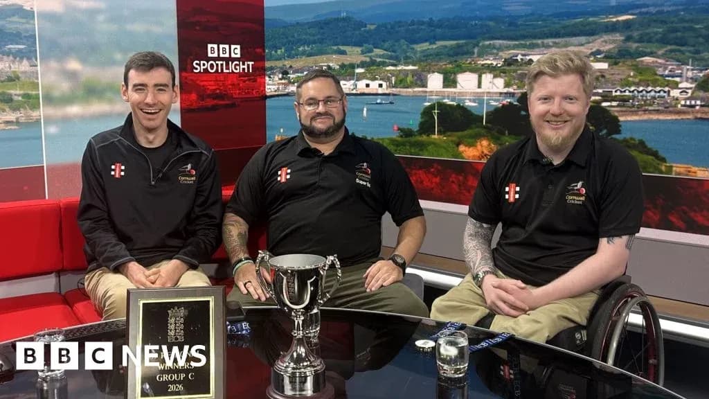 Three men seated with a trophy on set