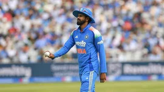 Cricketer in blue uniform holding a ball on field