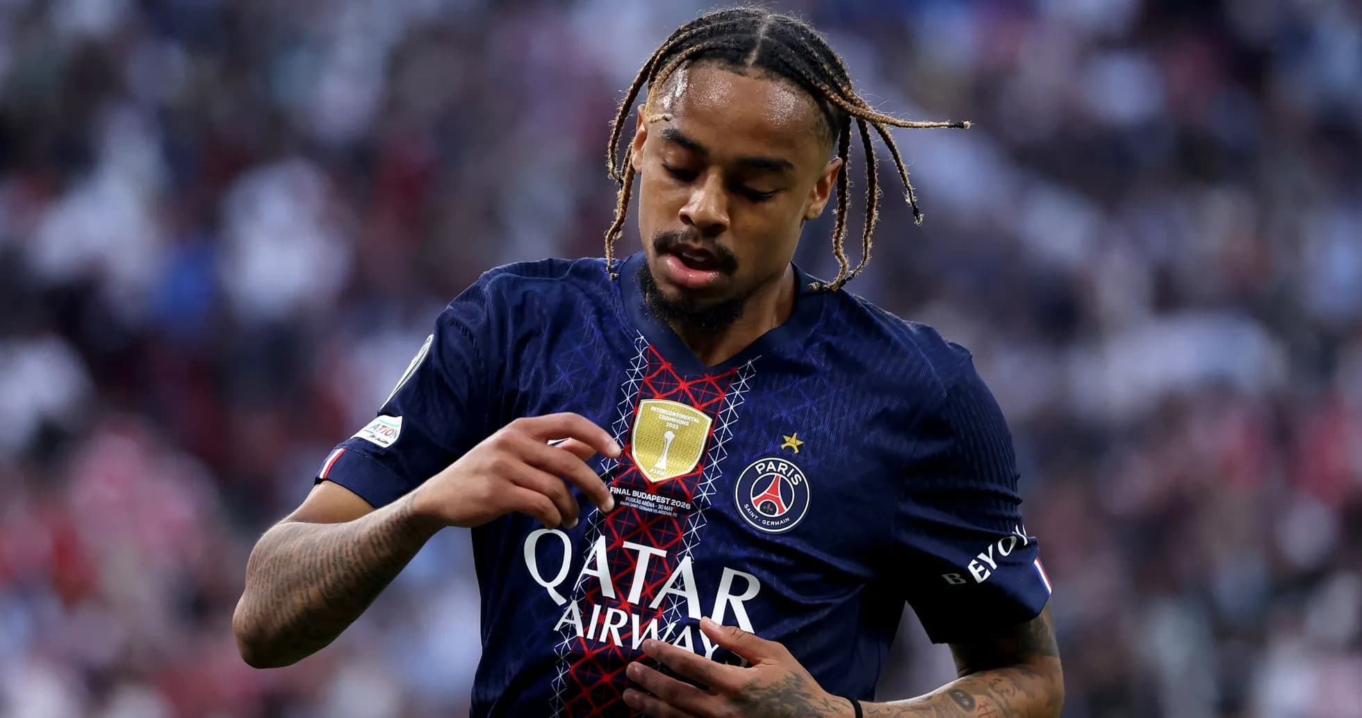 Player inspecting badge on PSG jersey during match
