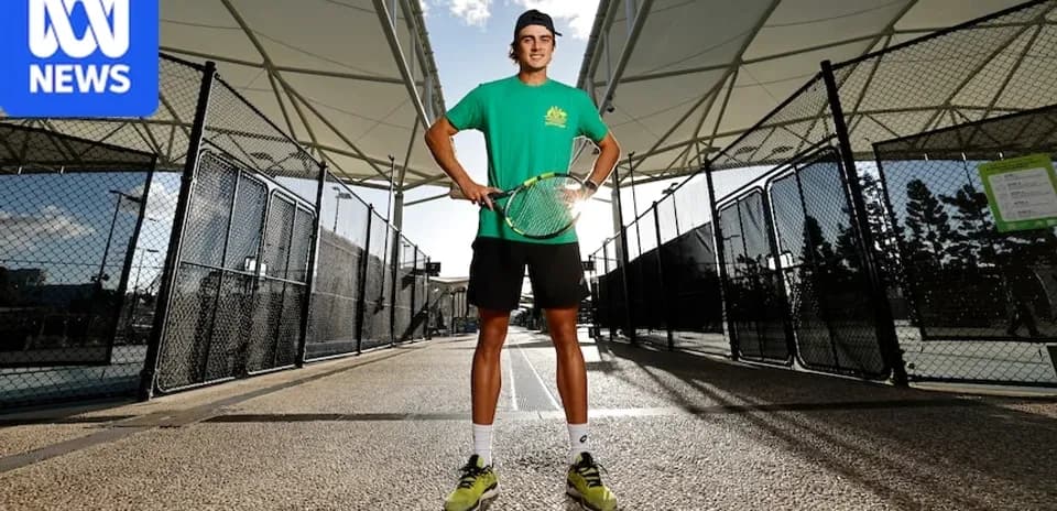 Young tennis player posing with racket on court