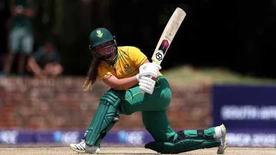 Cricketer batting during match in yellow and green uniform