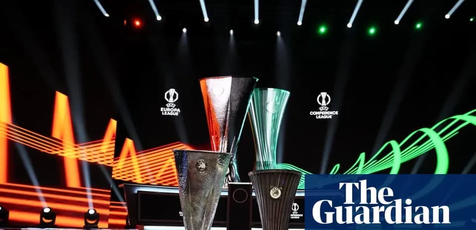 Three UEFA trophies displayed on stage with lighting