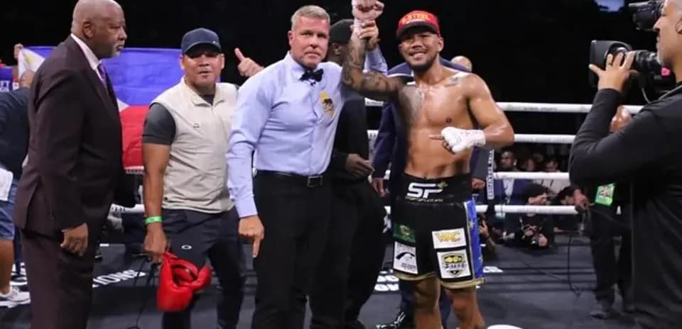 Boxer celebrating victory with referee and team members