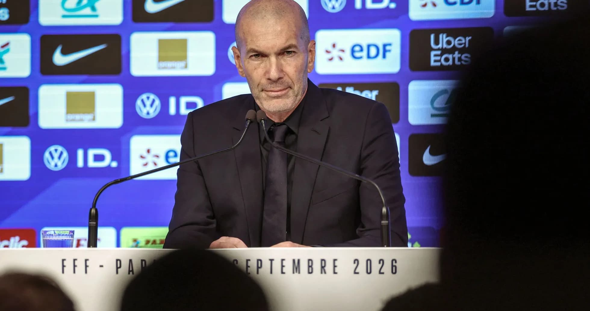 Manager speaking at press conference with sponsors backdrop
