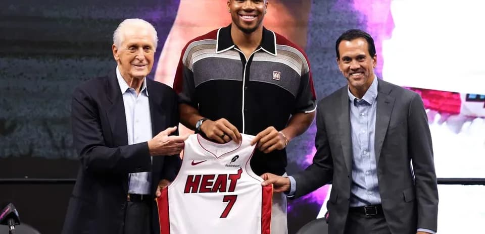 New player holding Miami Heat jersey with executives