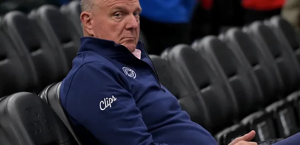 Man in Clippers attire sitting in empty arena