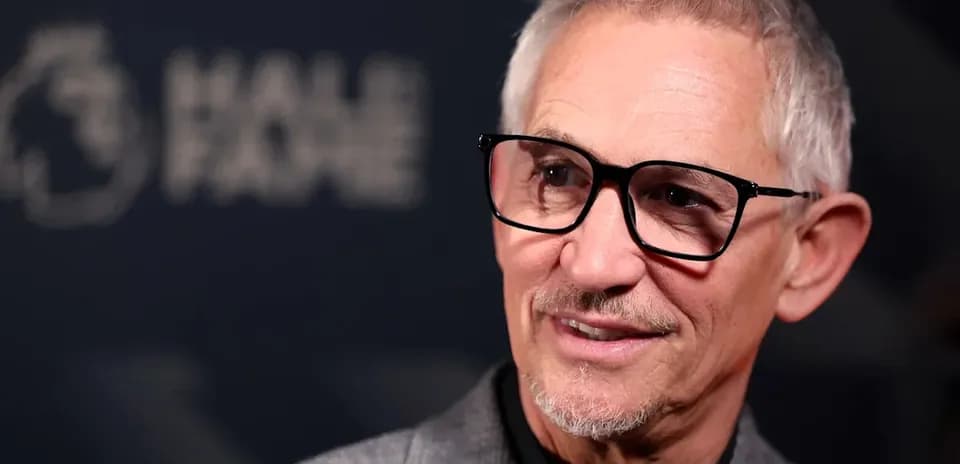 Man with glasses at a press event backdrop
