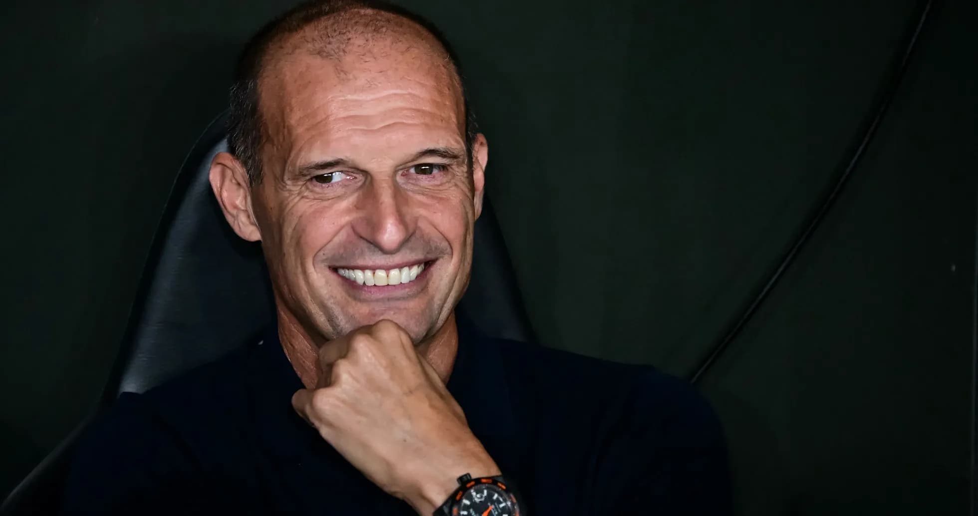Coach smiling while seated during press event