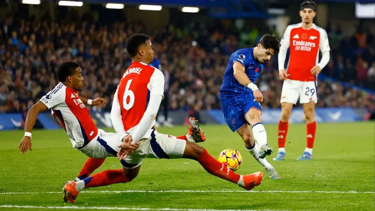 Chelsea player shooting while Arsenal defenders tackle