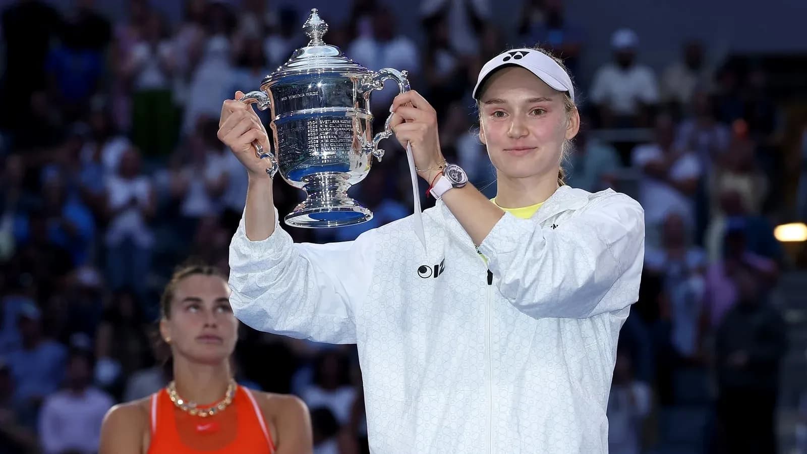 Player holding trophy with opponent in background Player holding trophy with opponent in background