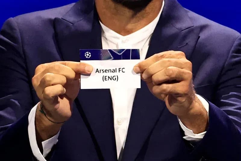 Person holding Arsenal FC draw card at event Person holding Arsenal FC draw card at event