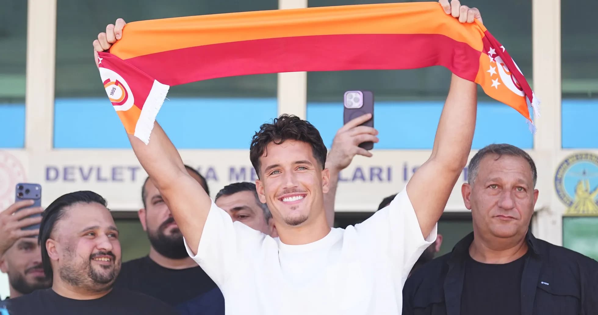 Player holding Galatasaray scarf at announcement event Player holding Galatasaray scarf at announcement event