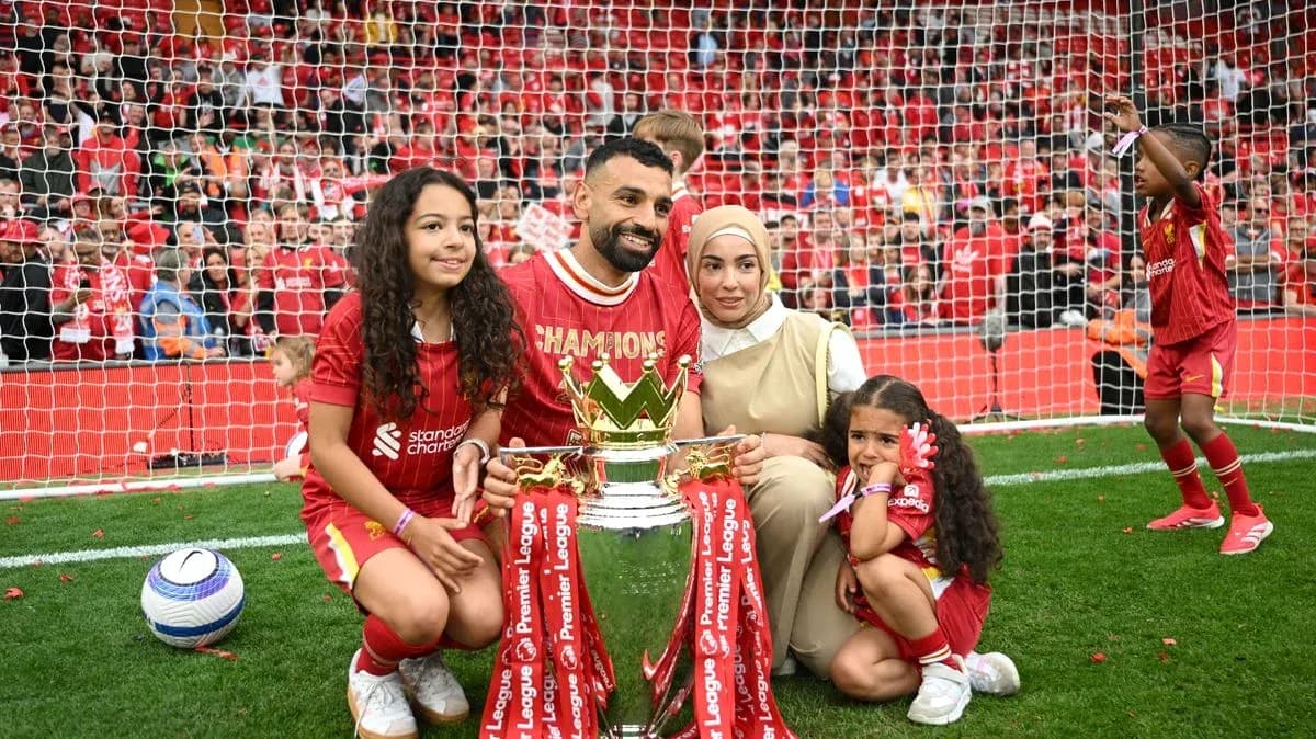 Player holding trophy with family on the pitch Player holding trophy with family on the pitch